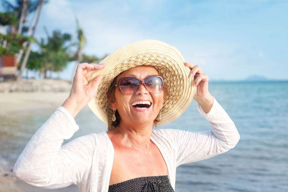 Smiling woman with sun hat on the beach.