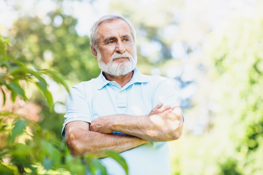 Man with folded arms standing outdoors.